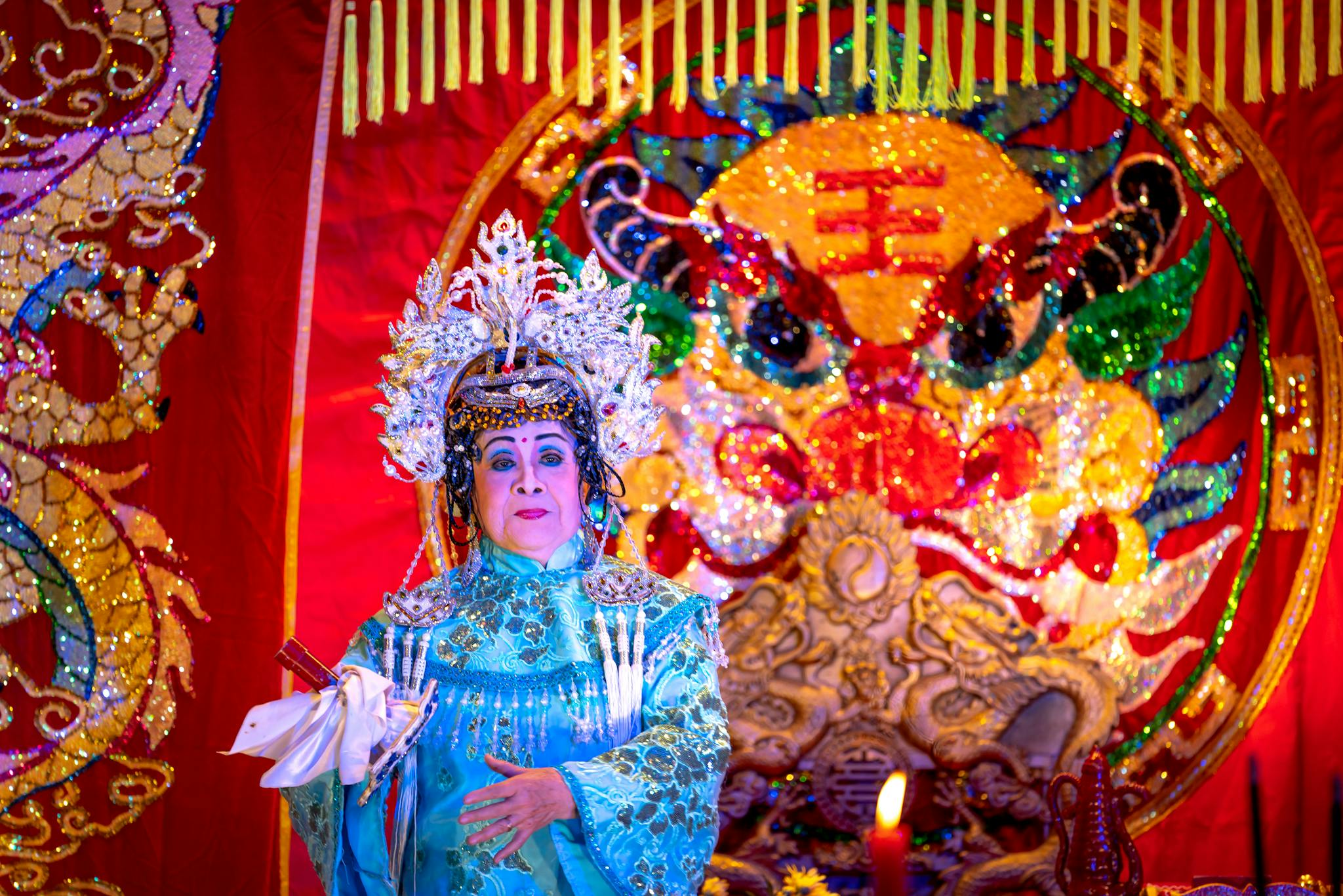 Chinese opera performer in vibrant traditional attire with ornate background.